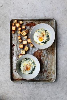 two bowls filled with food sitting on top of a metal baking pan next to tater tots