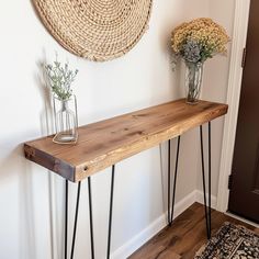 two vases with flowers sit on top of a wooden table in front of a door