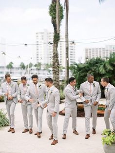 a group of men standing next to each other in front of palm trees and buildings