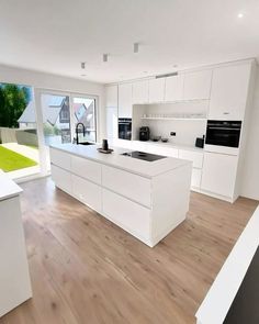 an empty kitchen with white cabinets and wood flooring