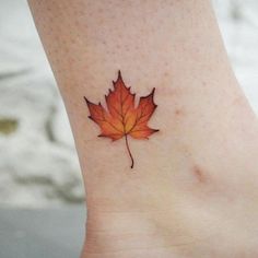 a small leaf tattoo on the ankle that looks like it has been painted red and yellow