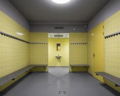 an empty bathroom with yellow walls and benches