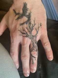 a person's hand with a tree tattoo on it and a bird flying above the tree