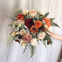 a bouquet of flowers is being held by someone's hand on a white background