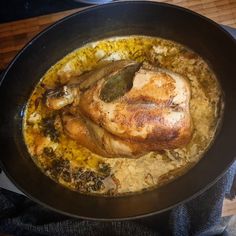 a chicken is cooked in a skillet on the stove with some herbs and spices