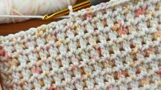 the crochet pattern is being worked on by someone using a knitting needle and yarn ball