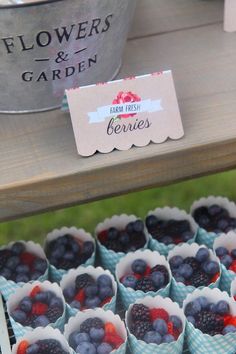 blueberries, raspberries and strawberries are in paper cups on a table