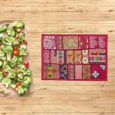 broccoli and other vegetables are on a cutting board next to a colorful quilt