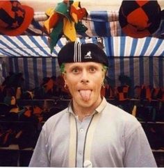 a man sticking his tongue out in front of an auditorium full of people wearing hats