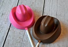 a pink toy hat sitting on top of a wooden table next to a chocolate lollipop