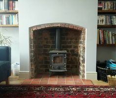 a living room with a brick fireplace and bookshelves