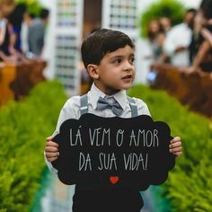 a young boy holding up a sign that says la vem o amor da sua vida