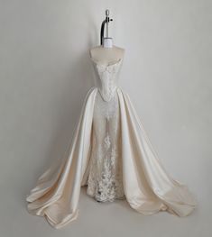 a wedding dress on display in front of a mannequin headdress dummy