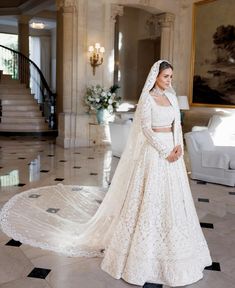 a woman in a white wedding gown and veil standing on the floor next to stairs