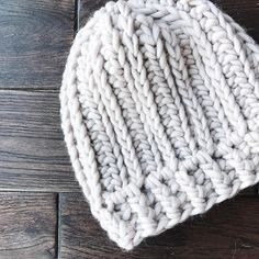 a white knitted hat sitting on top of a wooden floor