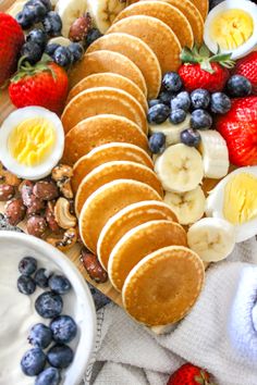 pancakes, fruit and yogurt are arranged on a platter to be eaten