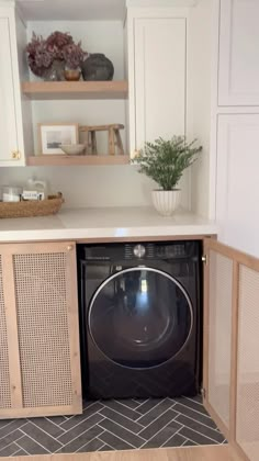 a washer and dryer in a small room with open cabinets on the wall