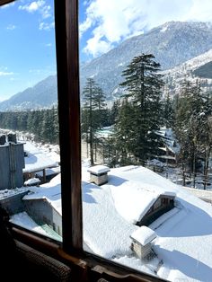 snow covered mountains and trees seen from a window in a building on the other side