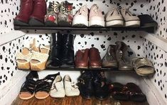 there are many pairs of shoes on the shelves in this closet with polka dot wallpaper