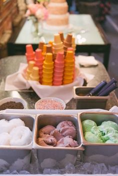 an assortment of ice creams in trays on a table next to other desserts