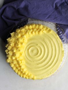 a yellow cake sitting on top of a white table next to a purple napkin and blue cloth