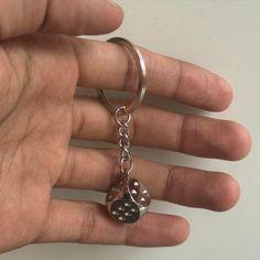 a hand holding a silver keychain with a paw print on it