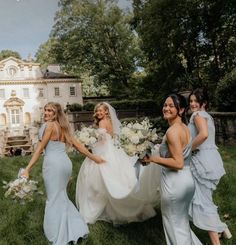 four bridesmaids walking in the grass with their bouquets and dresses flowing down