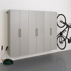 a bike mounted to the side of a white wall next to a gray storage cabinet