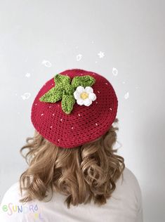 a woman wearing a crocheted hat with flowers on it's brim