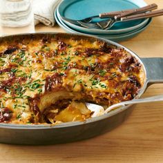 a casserole dish is shown with a serving spoon in it and plates on the side