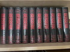 a row of black books sitting on top of a wooden shelf