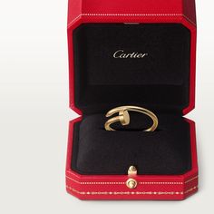 an open red box with a gold ring in it's center and the word cartier written on its side