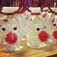 four plastic water bottles with red pom - poms on them sitting on a table