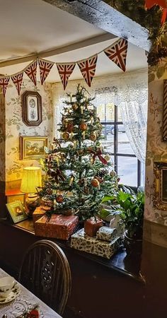 a decorated christmas tree sitting in the corner of a dining room next to a window