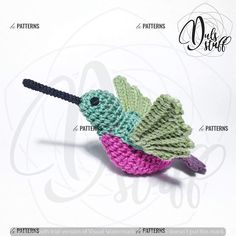 a crocheted bird is sitting on the ground with its wings spread out and it's head turned to the side