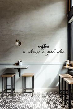 a coffee shop with tables and stools in front of a wall that says coffee is always a good idea