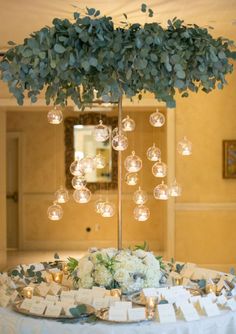 a table topped with a vase filled with flowers and lots of bubbles hanging from the ceiling