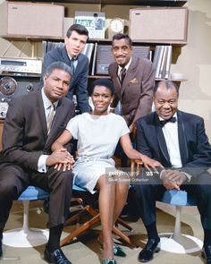 a group of people sitting next to each other in front of a desk with speakers