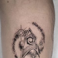 a black and white photo of a star trek symbol on the thigh with space around it