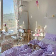 a dog laying on a bed in a room with a large window overlooking the city