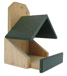 a wooden bird house with a green roof