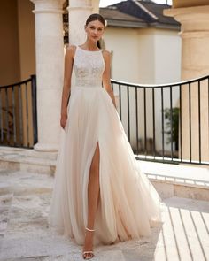 a woman in a wedding dress is standing on the steps near an iron fence and columns