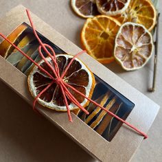 an orange cut in half sitting on top of a cardboard box next to other pieces of fruit