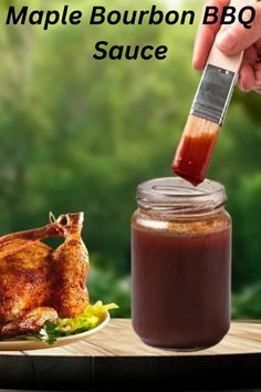 a person holding a brush over a jar of bbq sauce next to a chicken on a plate