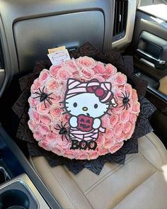 a hello kitty cake sitting on top of a car seat in front of a steering wheel