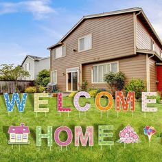 a welcome home sign in front of a house with flowers and houses on the lawn