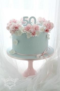 a blue cake with pink flowers on top and the number 50 written in frosting