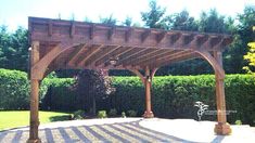 a wooden pergoline in the middle of a yard with trees and bushes behind it