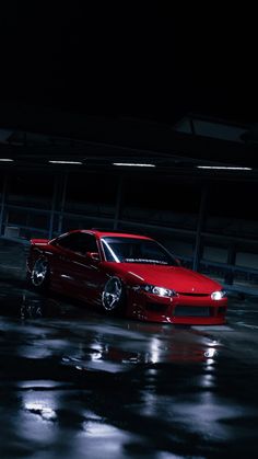 a red car parked in a parking lot at night