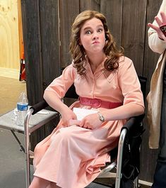 a woman in a pink dress sitting on a chair